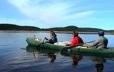Three Innu row across a lake in a traditional canoe