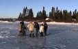 Sur la glace d'un lac en début d'hiver, on s'apprête à percer un trou pour pêcher