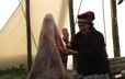 Inside a tent, Pelashe Bellefleur removes the fat from a caribou hide