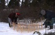 À l'extérieur, à quelques pouces de la neige, deux femmes étendent une peau de caribou pour la faire geler