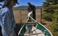 Two men adjust the outer shell of a traditional canoe