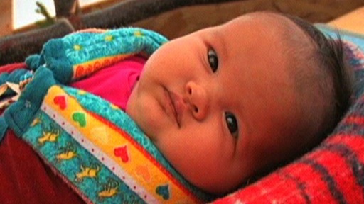 Close-up of an infant swaddled in a traditional blanket
