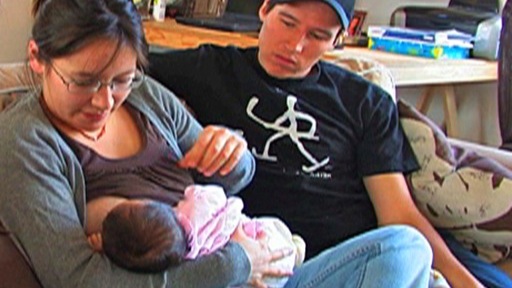 Young couple with baby: the mother is breastfeeding