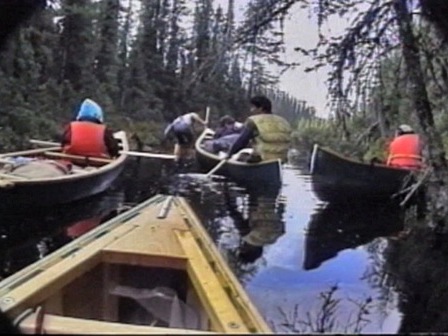 Group of Innu in canoes near a beaver dam