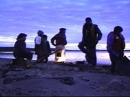A group of Innu rests by a fire in the early morning