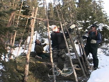 Jeunes Innus en train de monter une tente sur la neige