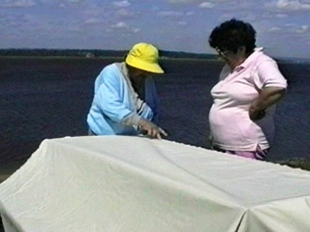 Deux femmes innues prennent la mesure d'une toile pour en faire une tente