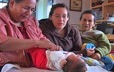 Grandmother, mother and aunt gathered around a newborn infant