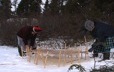 Outside, two women stretch a caribou hide a few inches from the snow, to freeze it