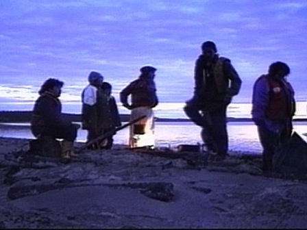 Près d'un feu au petit matin, un groupe d'Innus se repose